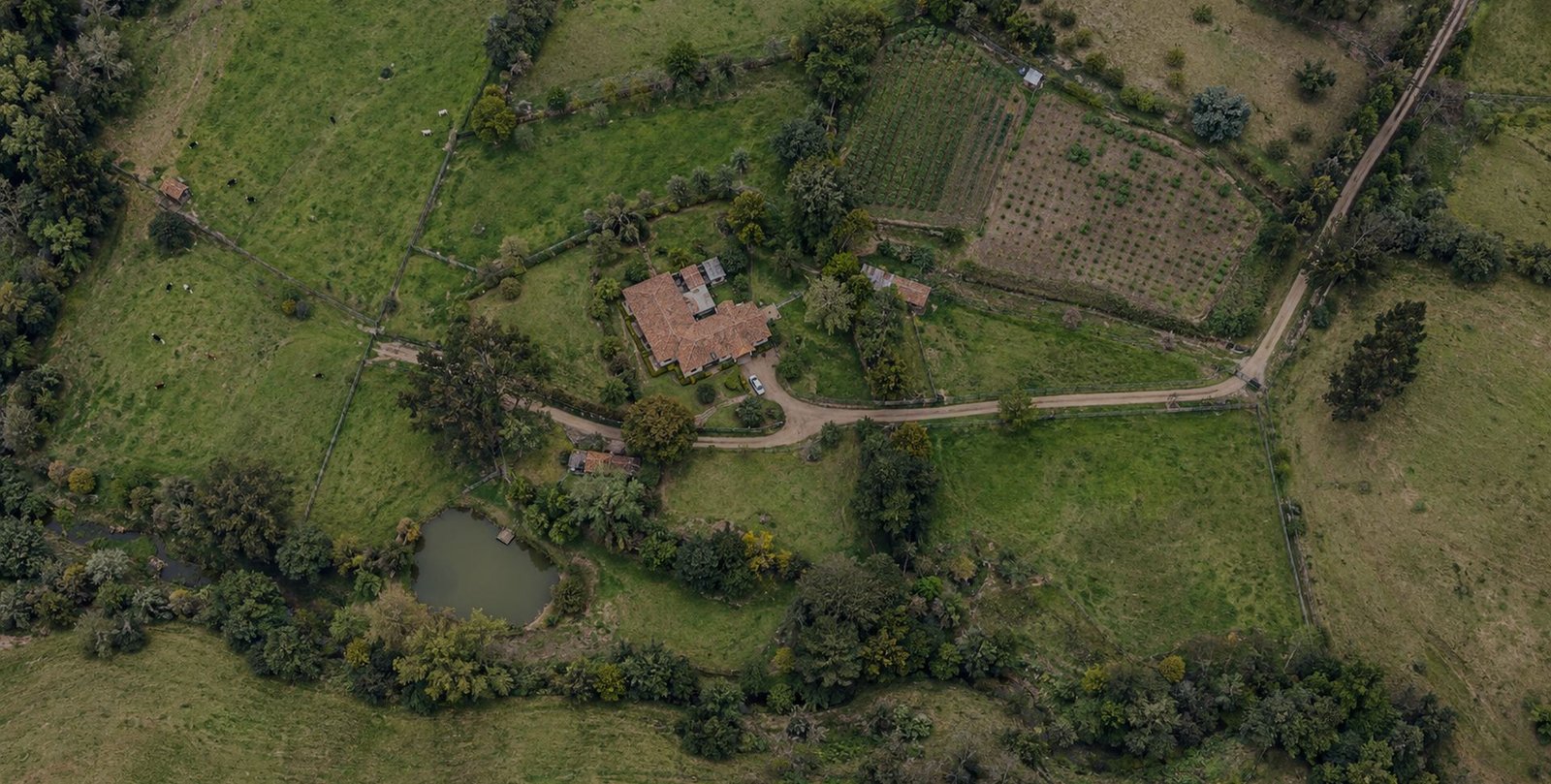 Vista aérea de un predio rural en la sabana de Bogotá con potreros, cerca viva, vivienda y un cuerpo de agua